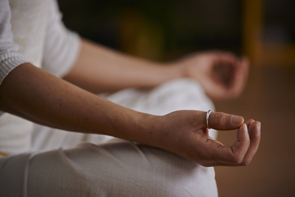 Meditující osoba se stříbrným prstenem na palci